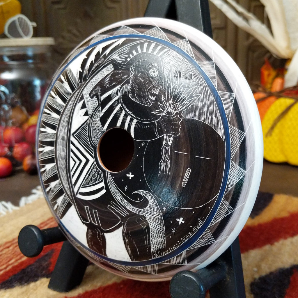 White and black pottery carved with a figure chanting, stars, and detailed patterns on the surface.