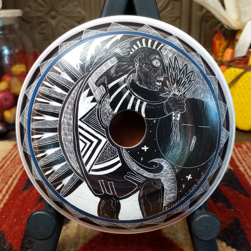 White and black pottery carved with a figure chanting, stars, and detailed patterns on the surface.