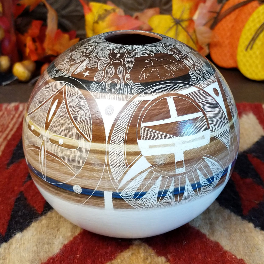 Detailed pot made from clay with vibrant, warm colors and intricate carvings creating a storytelling piece.