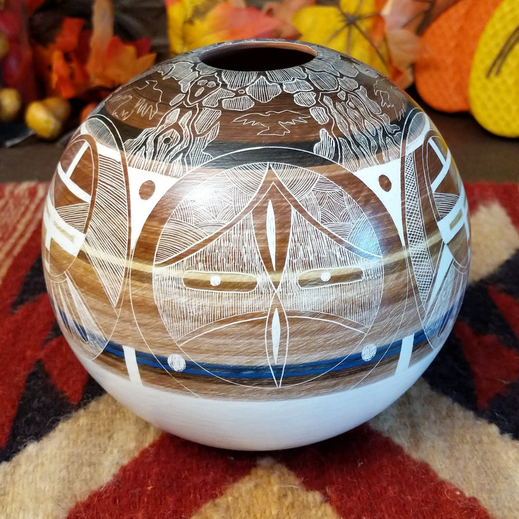 Detailed pot made from clay with vibrant, warm colors and intricate carvings creating a storytelling piece.
