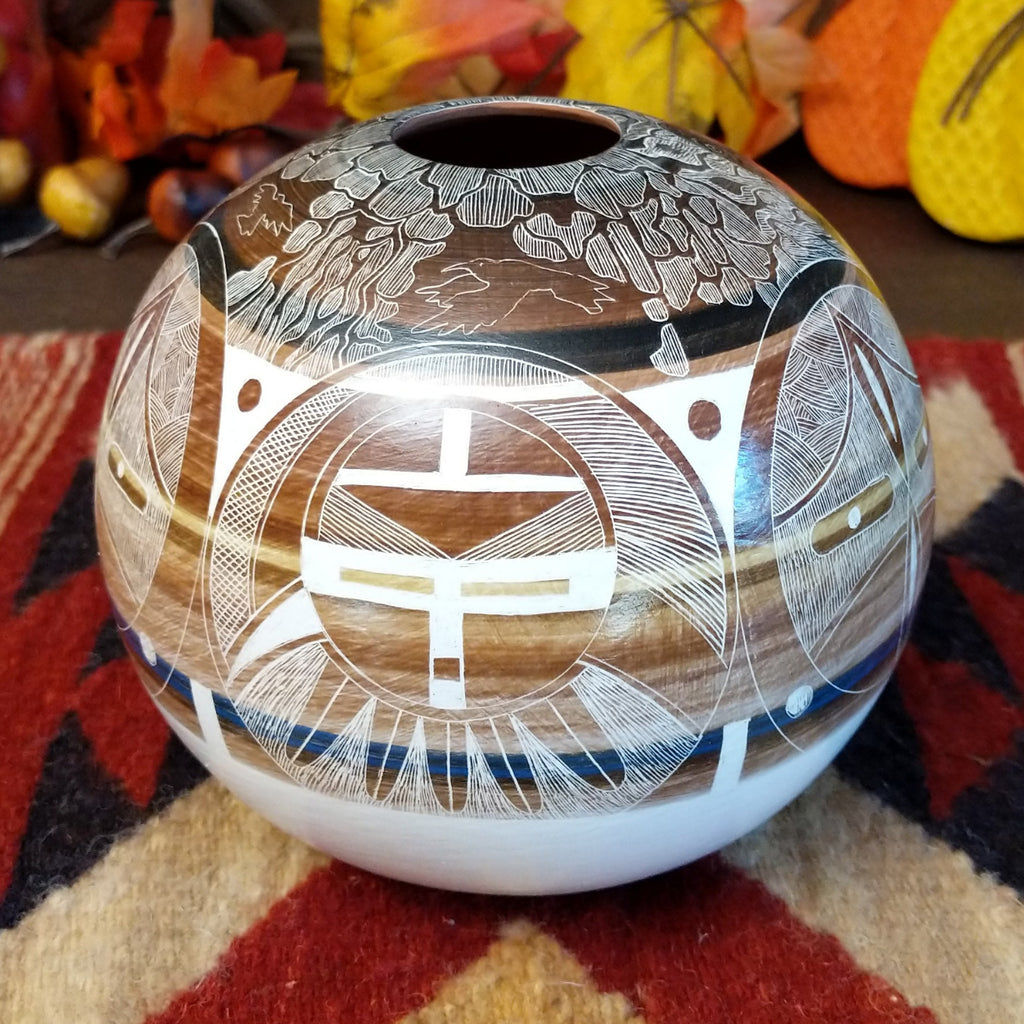 Detailed pot made from clay with vibrant, warm colors and intricate carvings creating a storytelling piece.