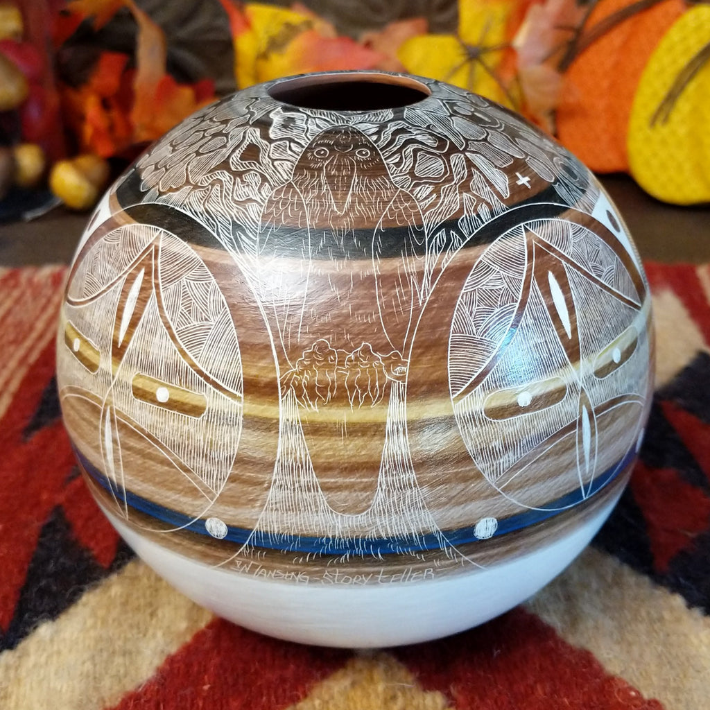 Detailed pot made from clay with vibrant, warm colors and intricate carvings creating a storytelling piece.