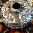 White clay with brown accents carved with detailed eyes and intricate designs.