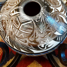 White clay with brown accents carved with detailed eyes and intricate designs.