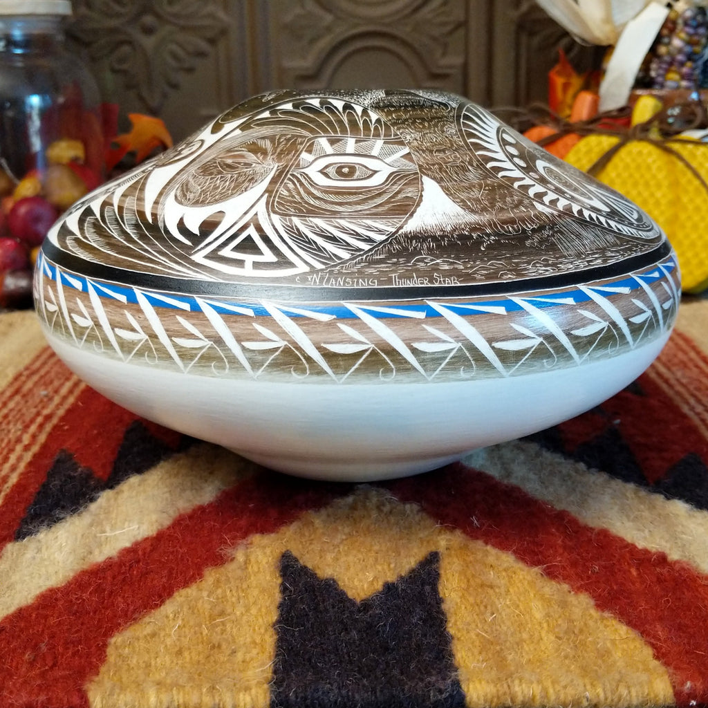 White clay with brown accents carved with detailed eyes and intricate designs.