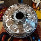 White clay with brown accents carved with detailed eyes and intricate designs.