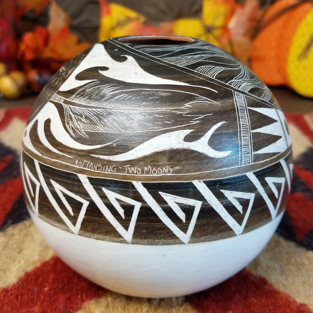 White clay with brown accents carved with intricate patterns, feathers, and moons.