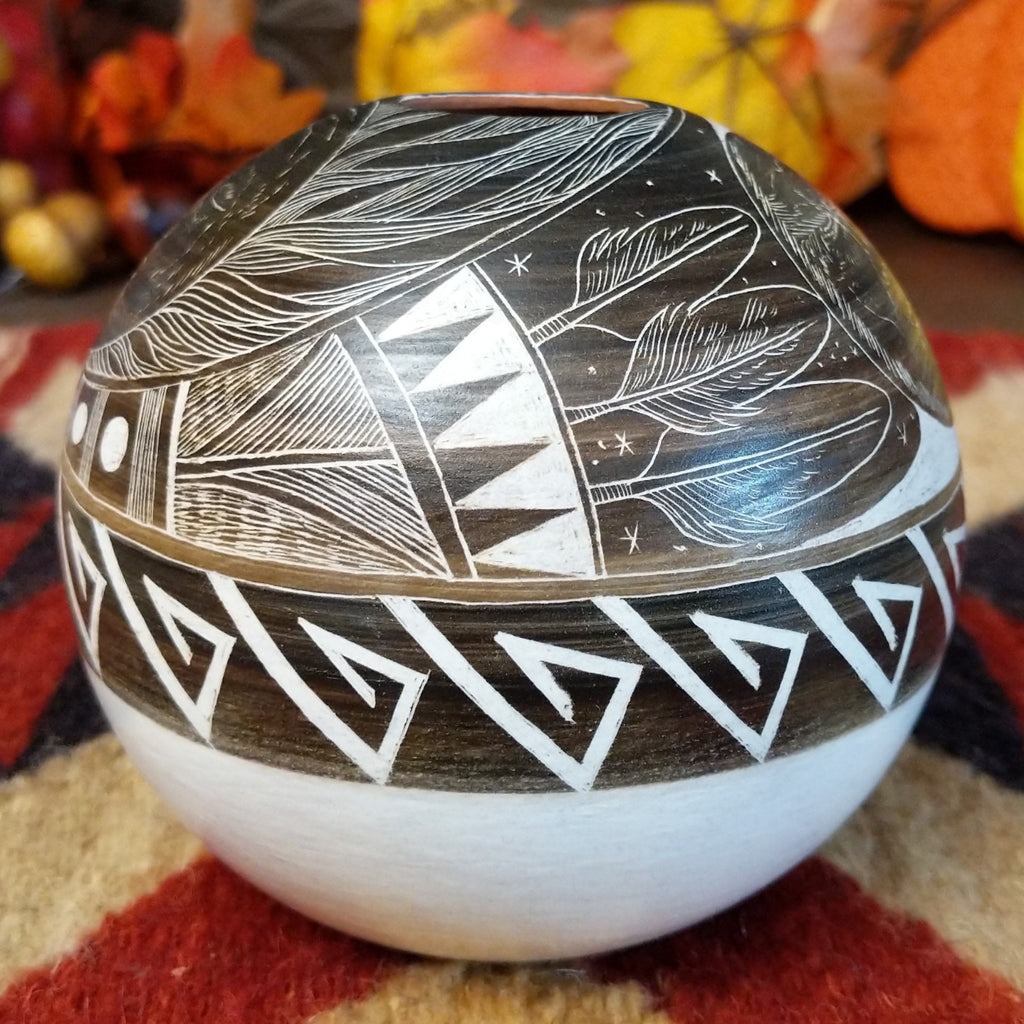 White clay with brown accents carved with intricate patterns, feathers, and moons.