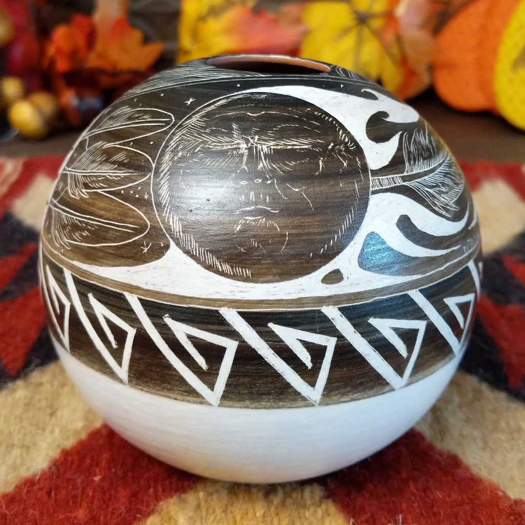 White clay with brown accents carved with intricate patterns, feathers, and moons.