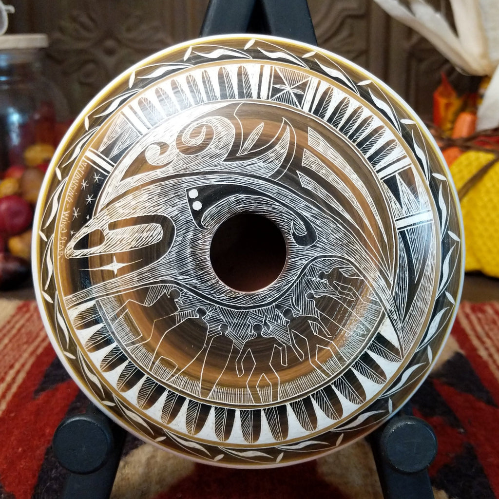 White clay pottery piece with warm tones, carved with depictions of people. wind, stars, and detailed patterns.
