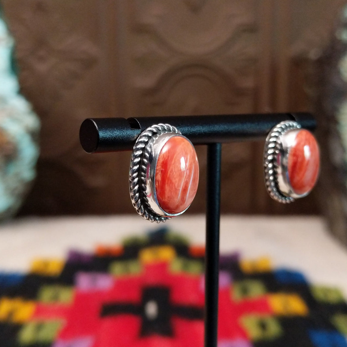 Warm Water Spiny Oyster Shell Oval Earrings by Priscilla Smith featuring polished coral-orange oval shell cabochons with natural color variations, set in silver with twisted rope-style borders; side view.