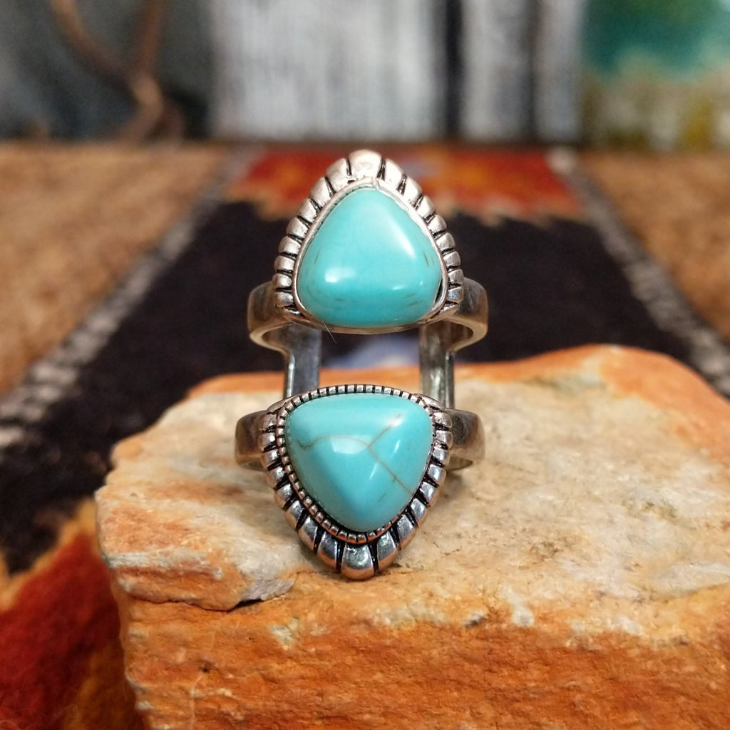 A nickel-free metal ring with a vibrant turquoise-colored stone, framed by a textured scalloped edge.