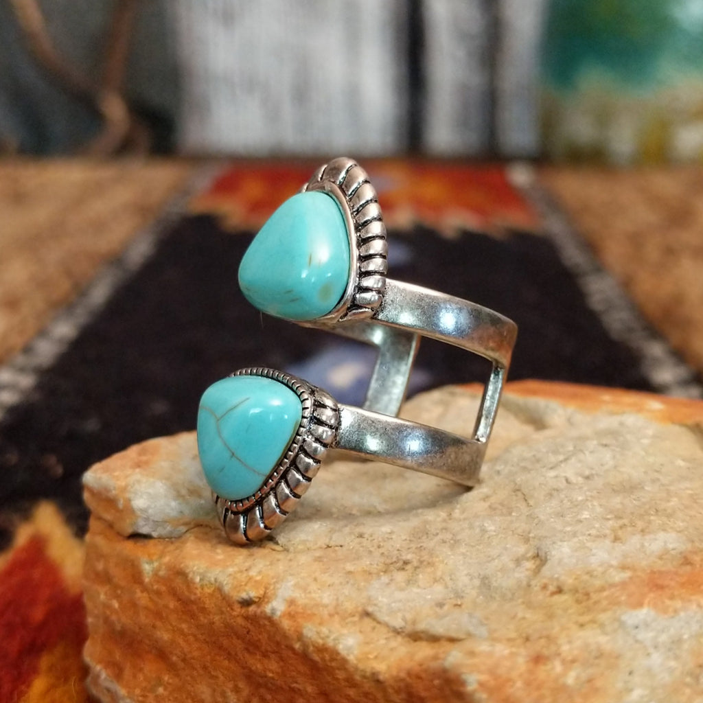 A nickel-free metal ring with a vibrant turquoise-colored stone, framed by a textured scalloped edge.