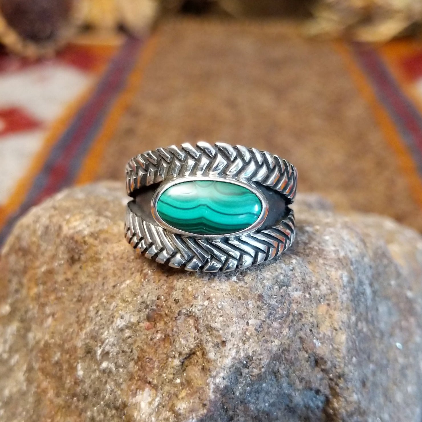 Sterling silver ring with oval malachite set in the bezel and weave patterned band.
