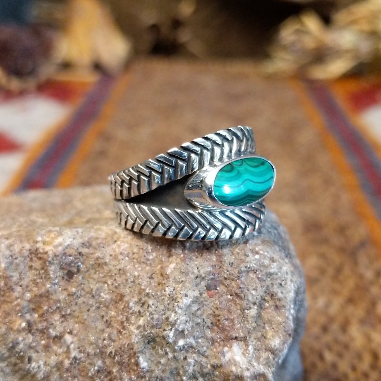 Sterling silver ring with oval malachite set in the bezel and weave patterned band.