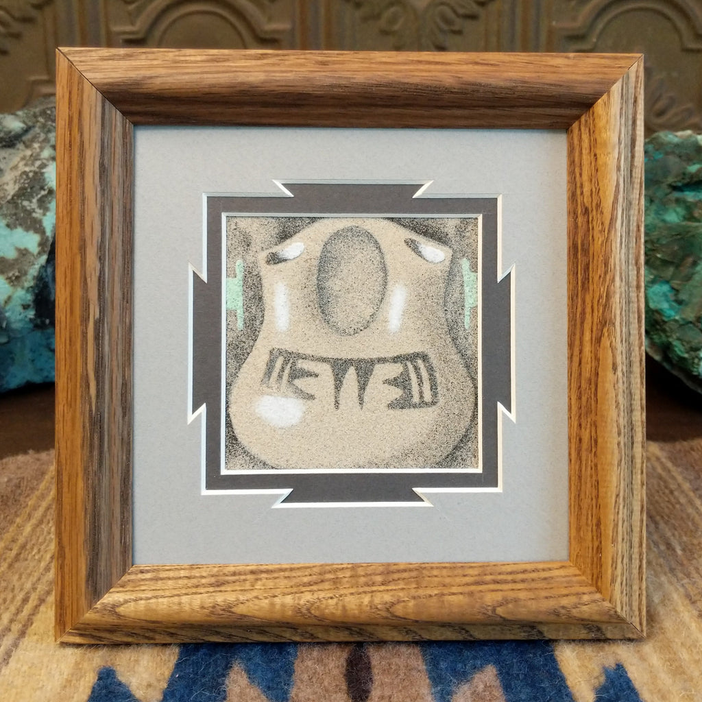 Sand painting of a wedding vase motif in muted tones within a wooden frame.