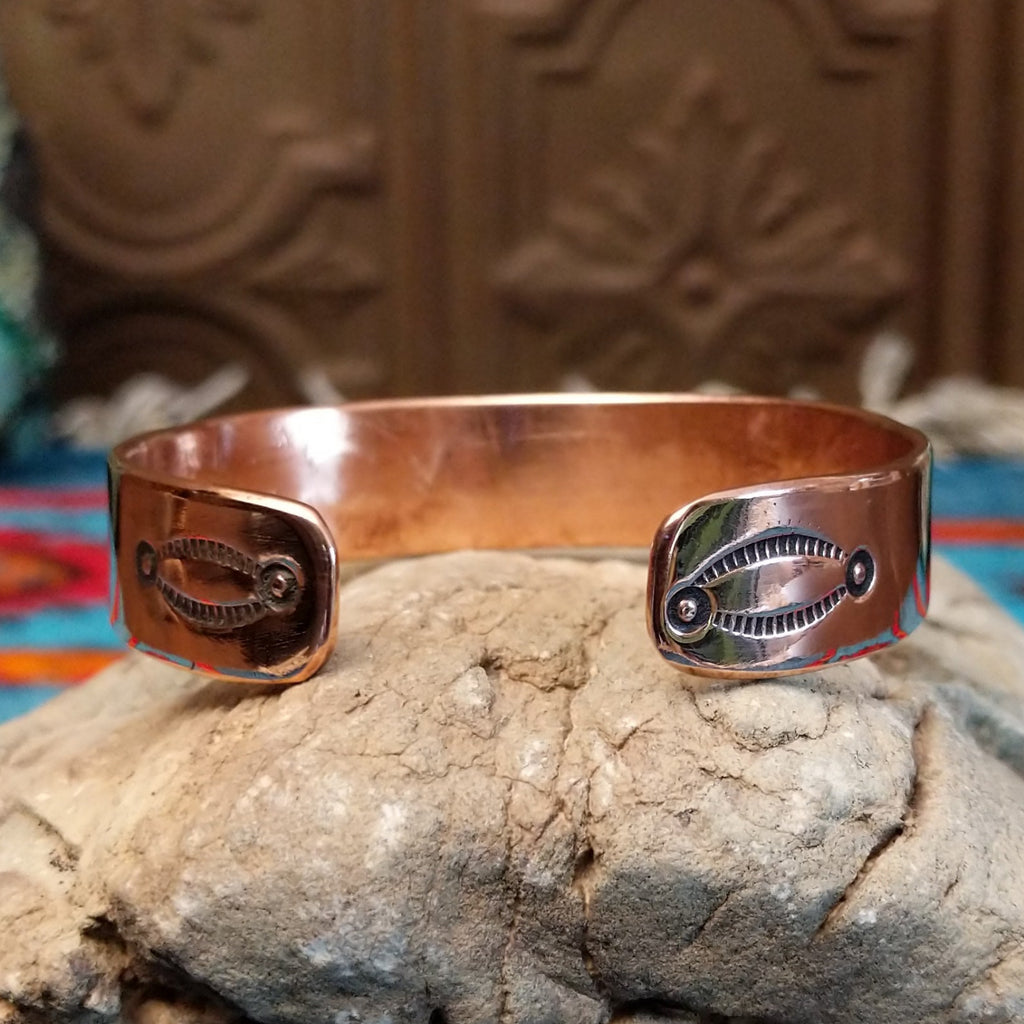 Copper and sterling silver bracelet with bear and whirlwind designs along the surface.