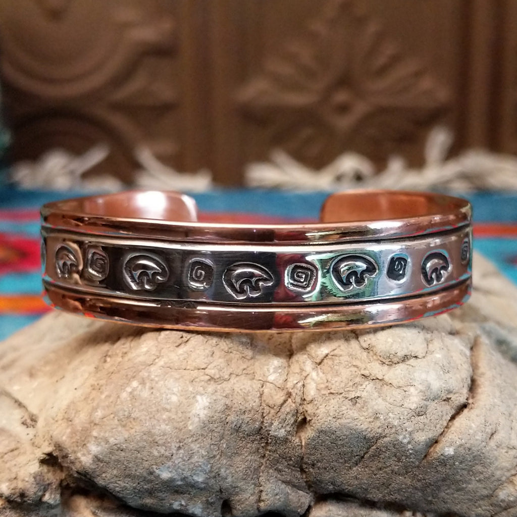 Copper and sterling silver bracelet with bear and whirlwind designs along the surface.