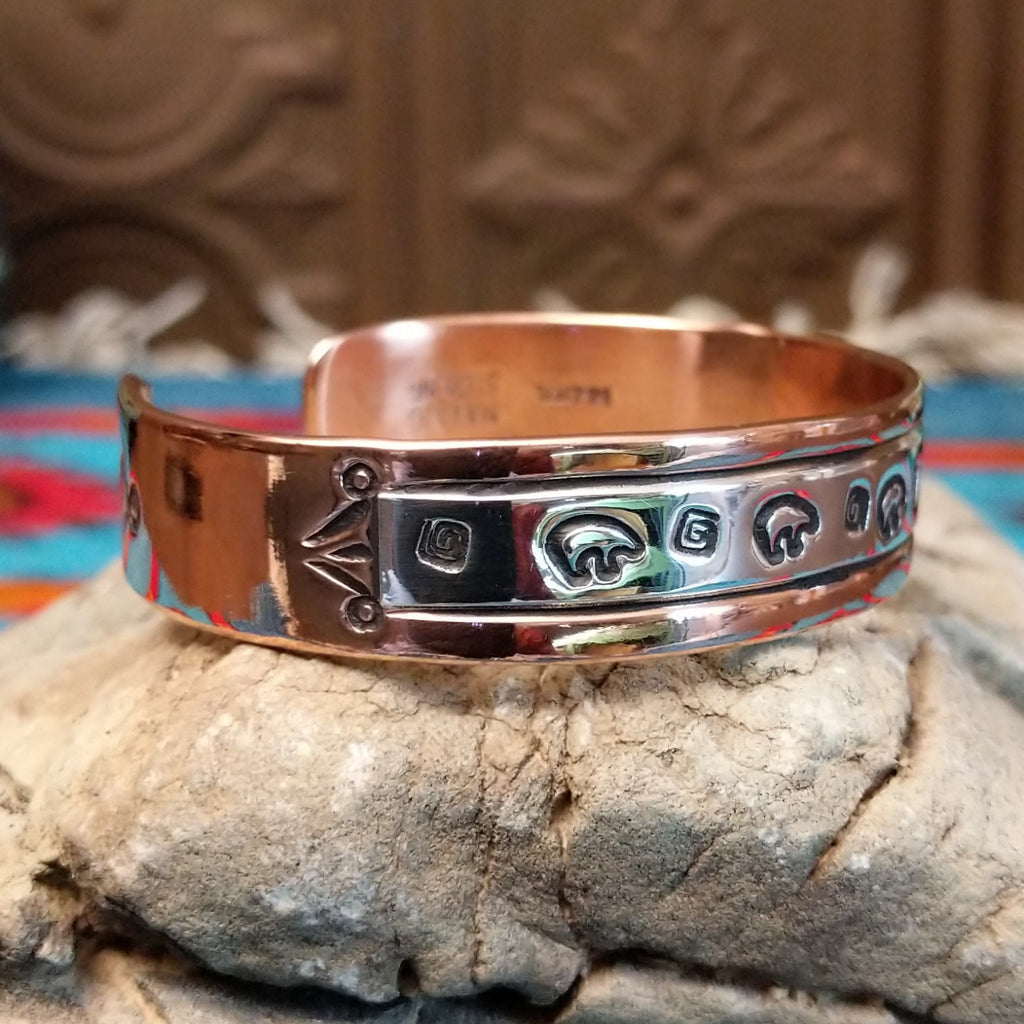 Copper and sterling silver bracelet with bear and whirlwind designs along the surface.