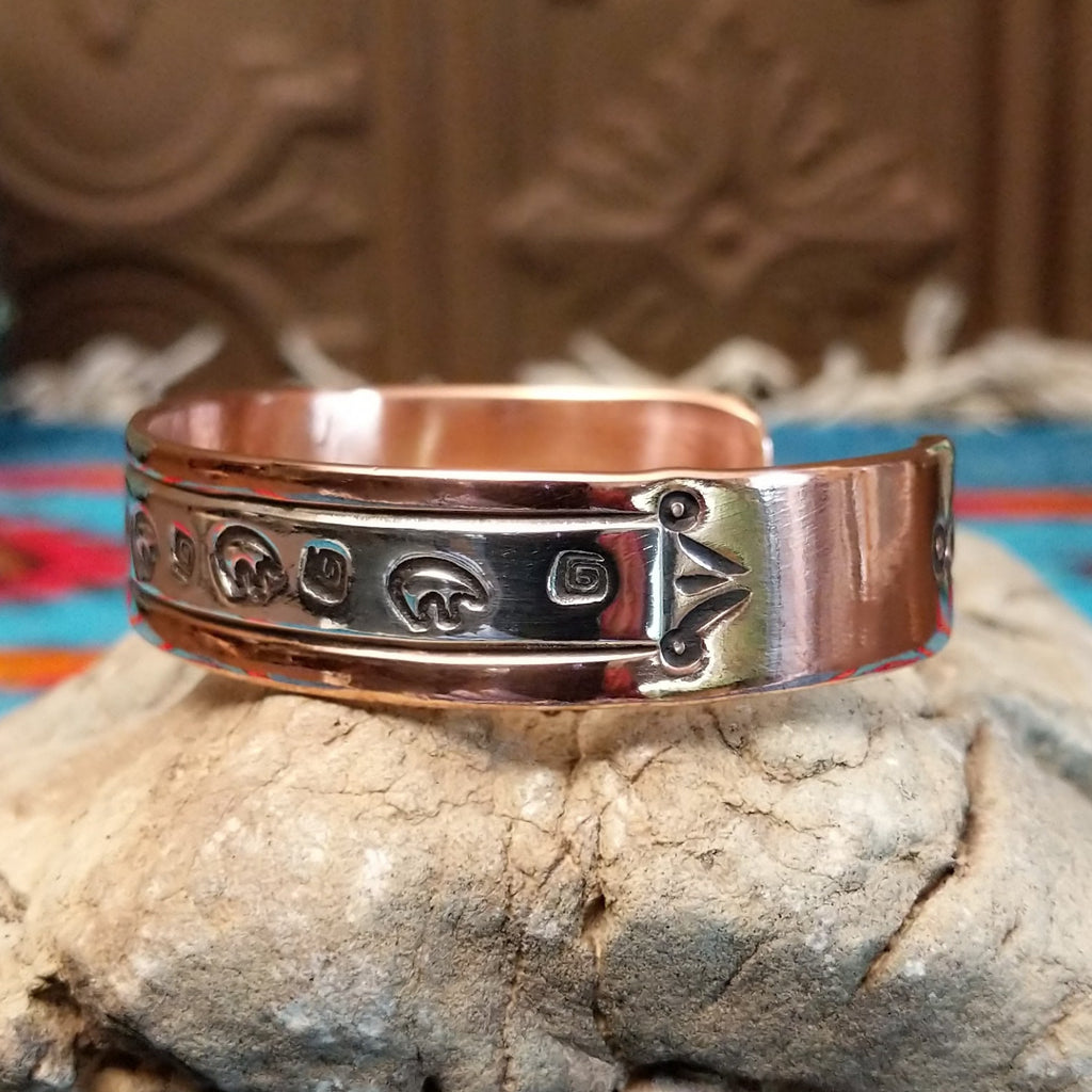 Copper and sterling silver bracelet with bear and whirlwind designs along the surface.