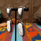 Southwestern-style Sterling Silver drop earrings featuring White Buffalo stones with natural black and gray matrix; side view.