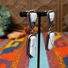 Southwestern-style Sterling Silver drop earrings featuring White Buffalo stones with natural black and gray matrix; side view.