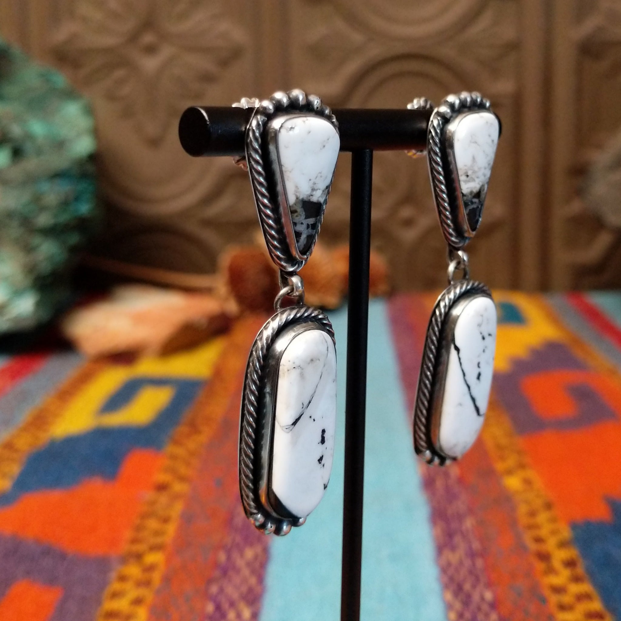 Southwestern-style Sterling Silver drop earrings featuring White Buffalo stones with natural black and gray matrix; side view.