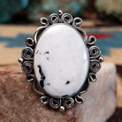 Sterling silver ring features white buffalo set in oval bezel with filigree pattern.