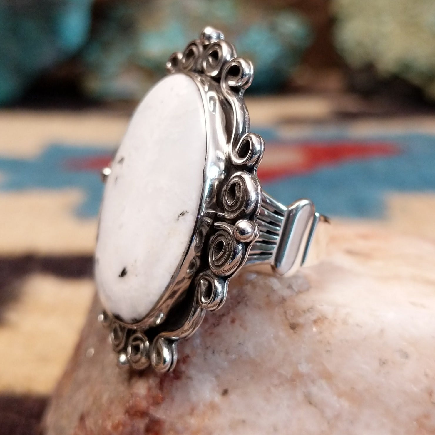 Sterling silver ring features white buffalo set in oval bezel with filigree pattern.