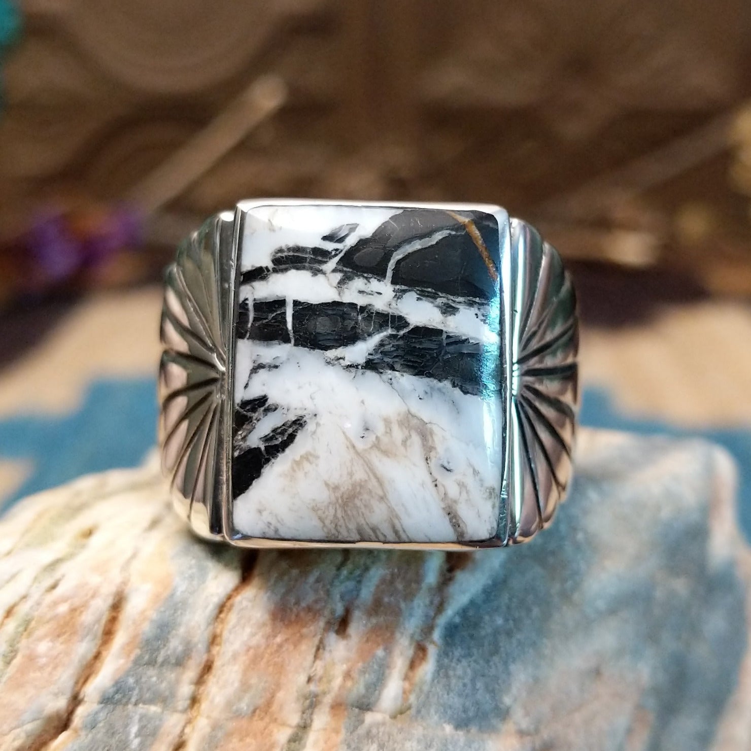 Sterling silver ring with white buffalo set in a rectangular bezel and stamped designs on the band.