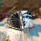 Sterling silver ring with white buffalo set in a rectangular bezel and stamped designs on the band.