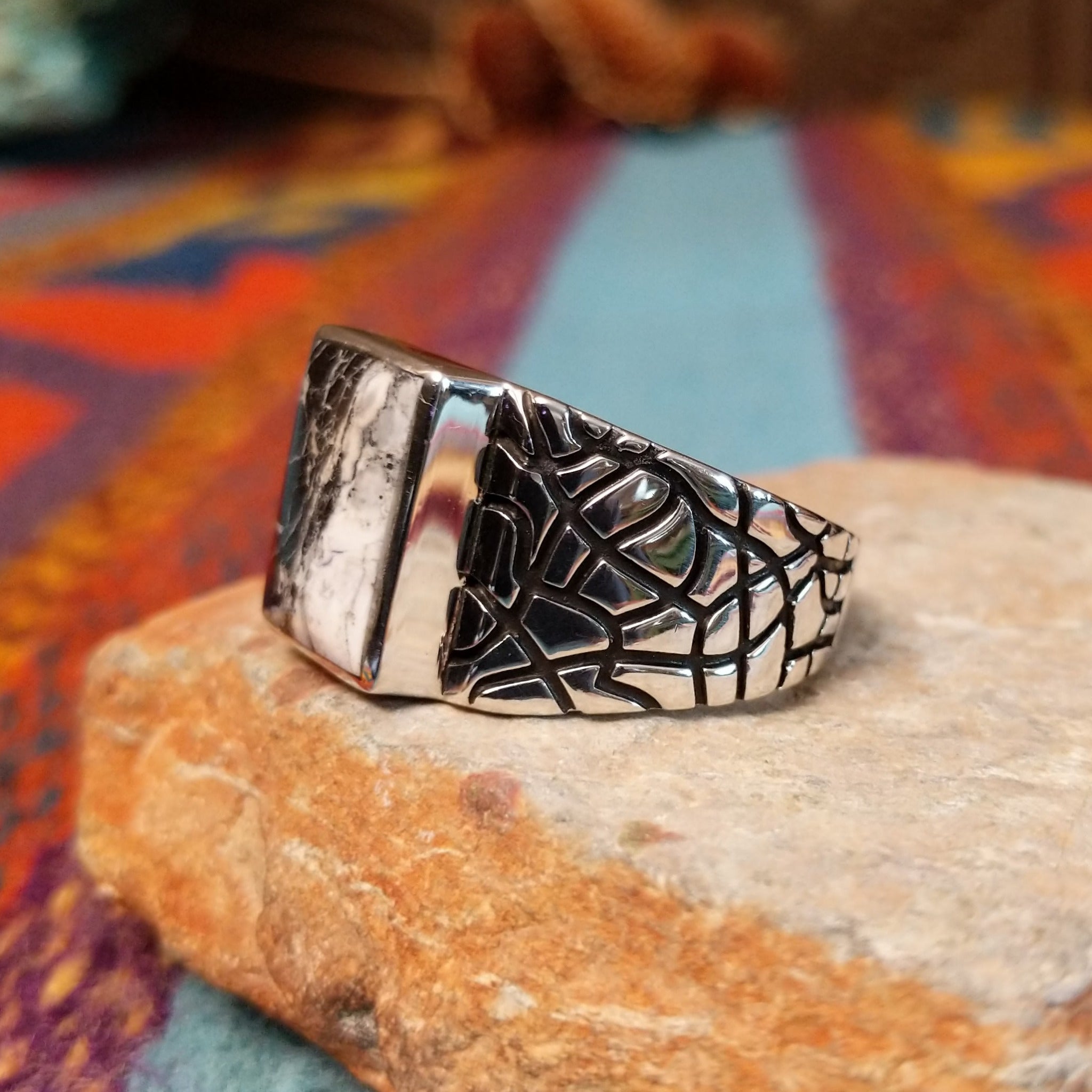 White Buffalo Ring by Terry Wood featuring a rectangular black-and-white stone with dramatic natural veining, set in polished silver with an intricate geometric openwork band; side view.