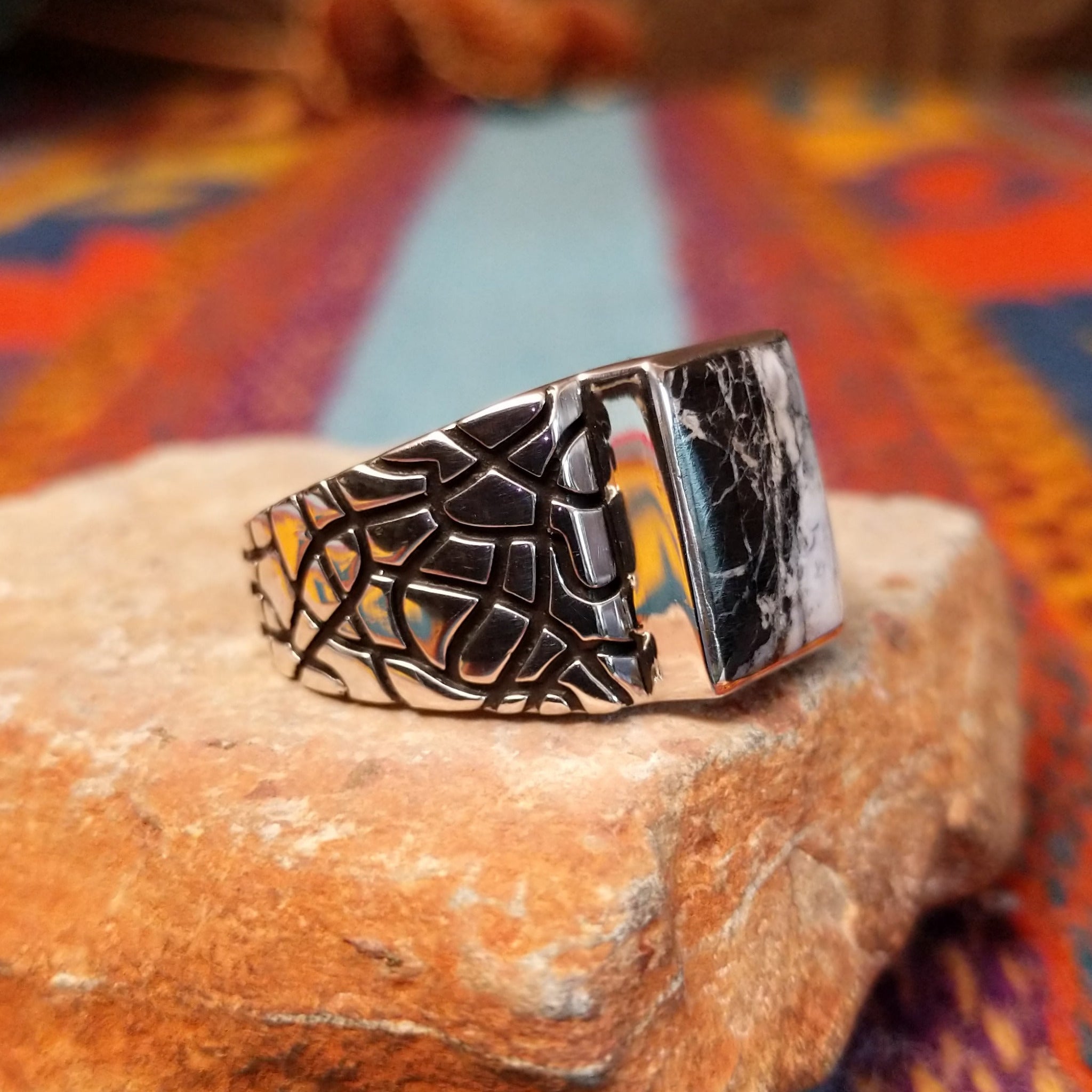 White Buffalo Ring by Terry Wood featuring a rectangular black-and-white stone with dramatic natural veining, set in polished silver with an intricate geometric openwork band; side view.