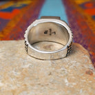 White Buffalo Ring by Terry Wood featuring a rectangular black-and-white stone with dramatic natural veining, set in polished silver with an intricate geometric openwork band; underside view.