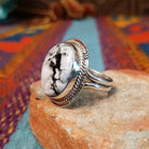 White Buffalo Round Ring by Larson Lee featuring a large White Buffalo stone with black matrix set in Sterling Silver with twisted rope and geometric silver detailing; side view.