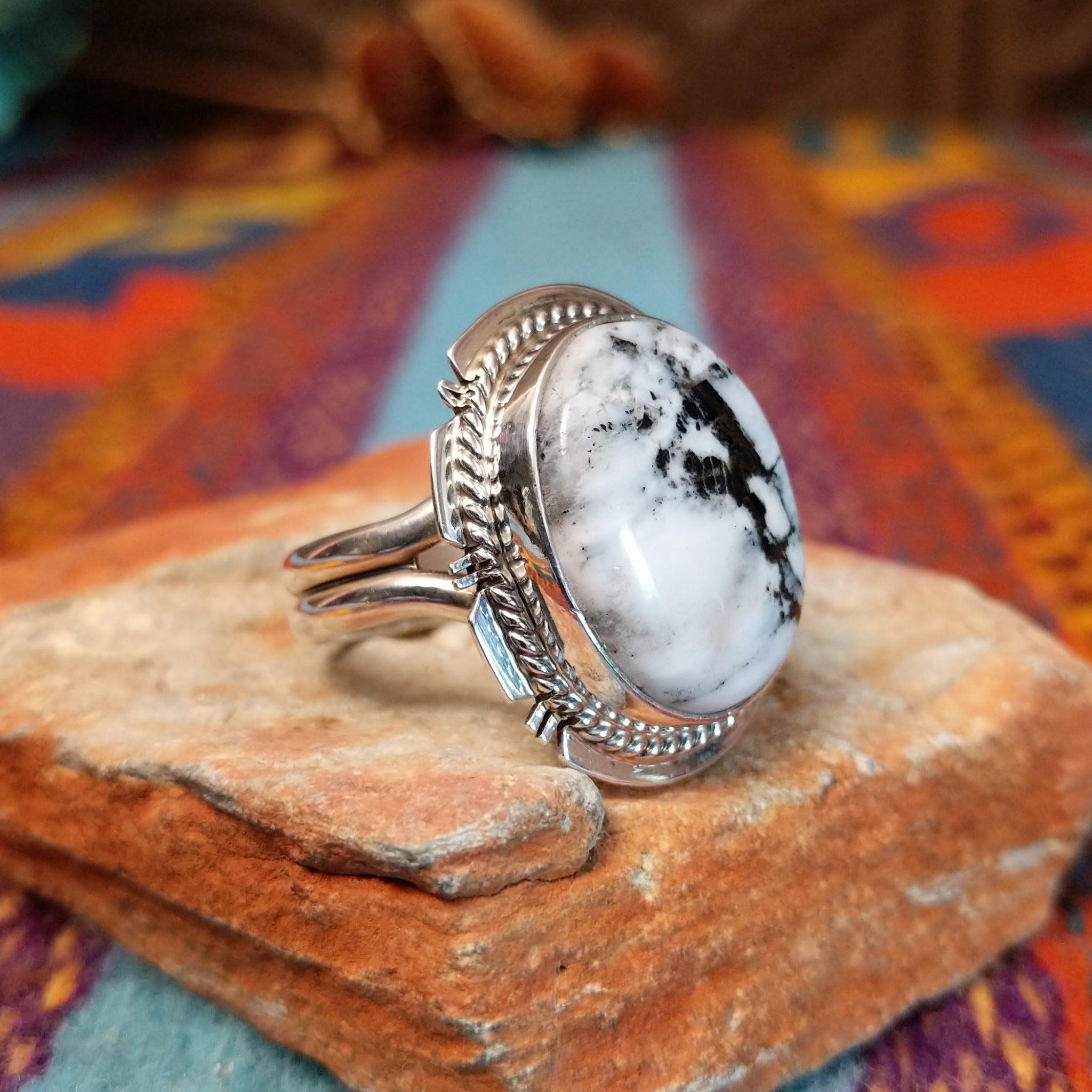 White Buffalo Round Ring by Larson Lee featuring a large White Buffalo stone with black matrix set in Sterling Silver with twisted rope and geometric silver detailing; side view.