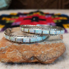 White manmade opal inlay hoop earrings by Malcolm Chavez with twisted silver borders.