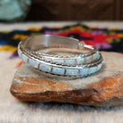 White manmade opal inlay hoop earrings by Malcolm Chavez with twisted silver borders.