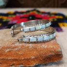 White manmade opal inlay hoop earrings by Malcolm Chavez with twisted silver borders.