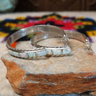 White manmade opal inlay hoop earrings by Malcolm Chavez with twisted silver borders.