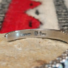 Silver cuff by Raymond Coriz featuring a single row of oval white manmade opals with colorful flashes of pink, green, yellow, and blue; artisan and Sterling Silver stamp.