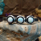 Sterling silver cuff bracelet with white, manmade opal set in a trio of round bezels, framed by showbox design and geometric setting.