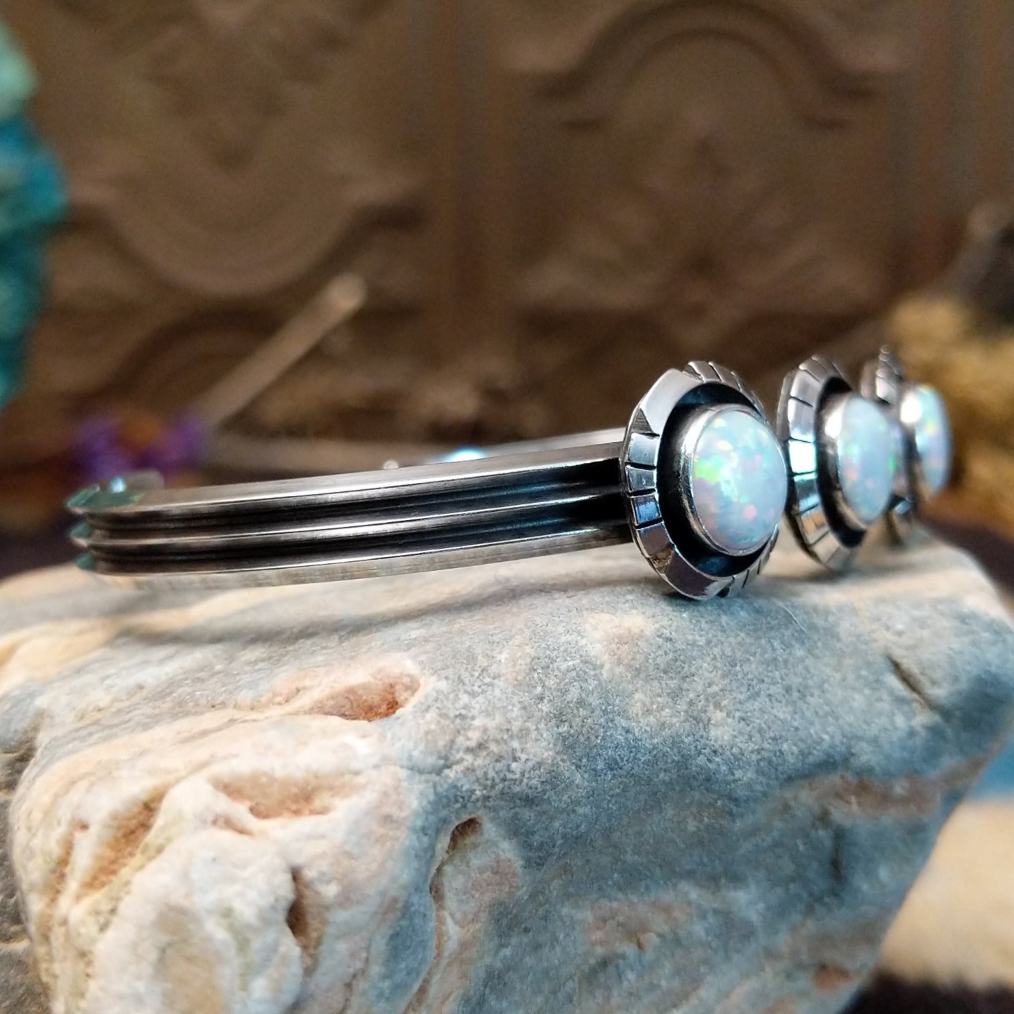 Sterling silver cuff bracelet with white, manmade opal set in a trio of round bezels, framed by showbox design and geometric setting.