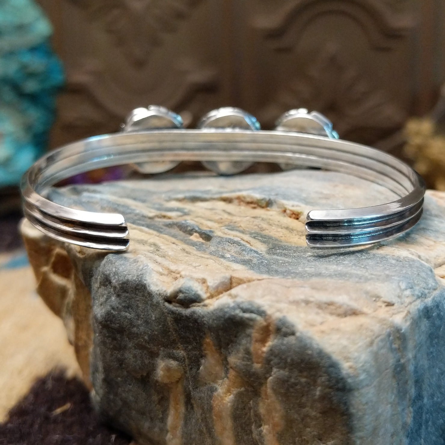 Sterling silver cuff bracelet with white, manmade opal set in a trio of round bezels, framed by showbox design and geometric setting.