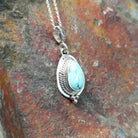 Handcrafted sterling silver White Water turquoise pendant by Lucy Jake, featuring a natural blue-green stone in a traditional Navajo setting; side view.
