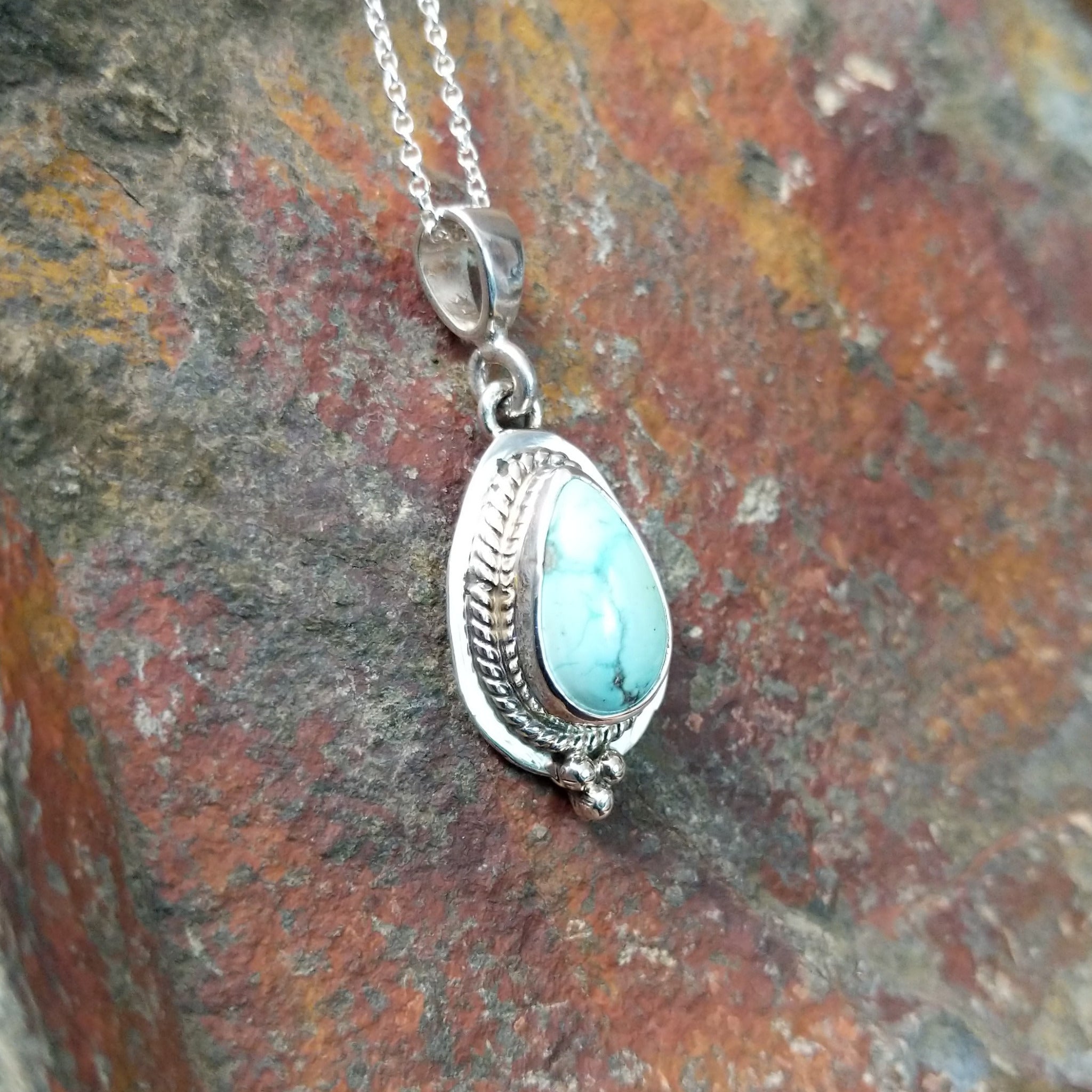 Handcrafted sterling silver White Water turquoise pendant by Lucy Jake, featuring a natural blue-green stone in a traditional Navajo setting; side view.