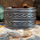 Sterling silver cuff bracelet with raised zigzag motifs and hand-stamped decorative bands.