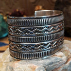 Sterling silver cuff bracelet with raised zigzag motifs and hand-stamped decorative bands.