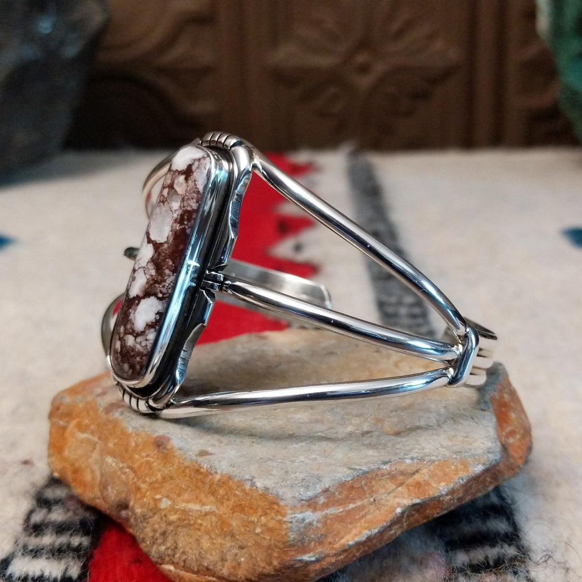 Silver cuff by Amory Begay featuring a long rectangular Wild Horse stone with creamy white and brown matrix, framed by polished silver and curved split bands; side view.