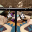 Handcrafted sterling silver navette earrings featuring natural Wild Horse stone with creamy white and rich brown patterns, accented by detailed silver beadwork and French hook ear wires.